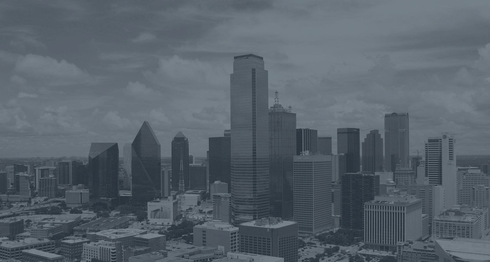 A city skyline with tall modern skyscrapers under a partly cloudy sky.