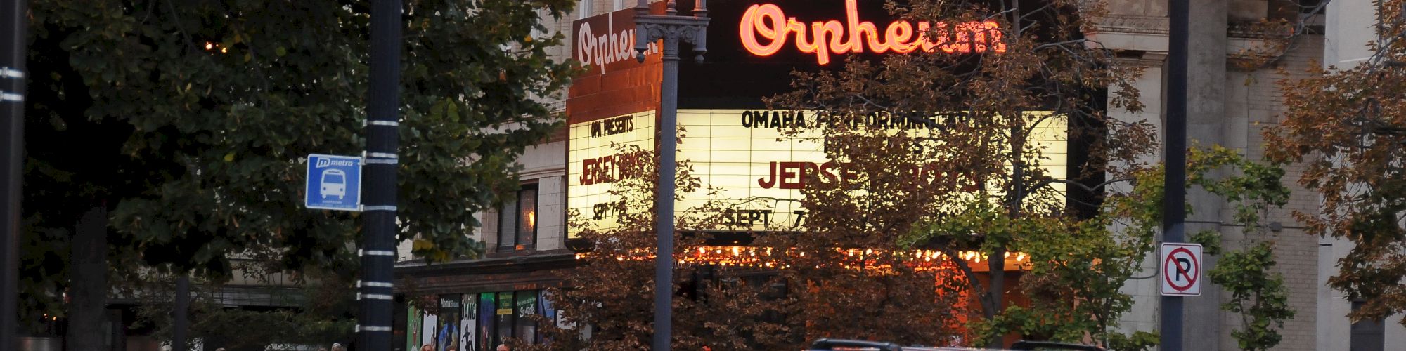 The image shows cars driving past the Orpheum Theater marquee, with people gathered outside.