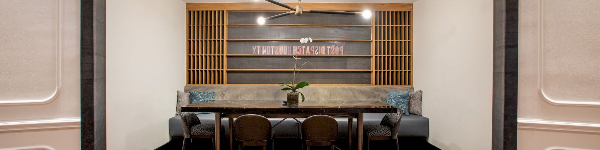 A modern dining area with a wooden table, chairs, and a bench, surrounded by minimalist decor and soft lighting.