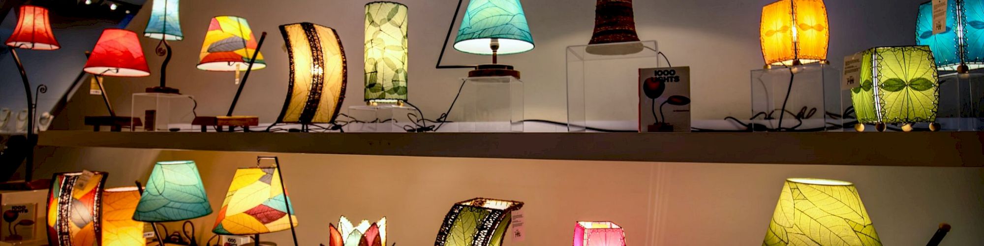 A display of various colorful lamps in a store, featuring different shapes and sizes, arranged on shelves.