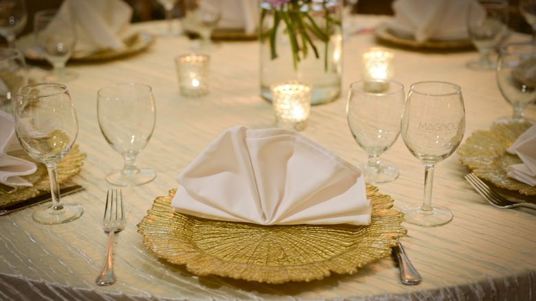 A table set for a formal occasion with elegant tableware, folded napkins, and candles, creating a sophisticated ambiance.