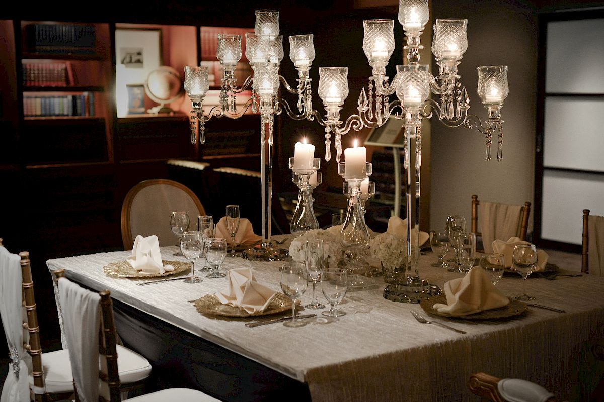 A dining table elegantly set with crystal chandeliers, wine glasses, and folded napkins, creating a luxurious and inviting ambiance.