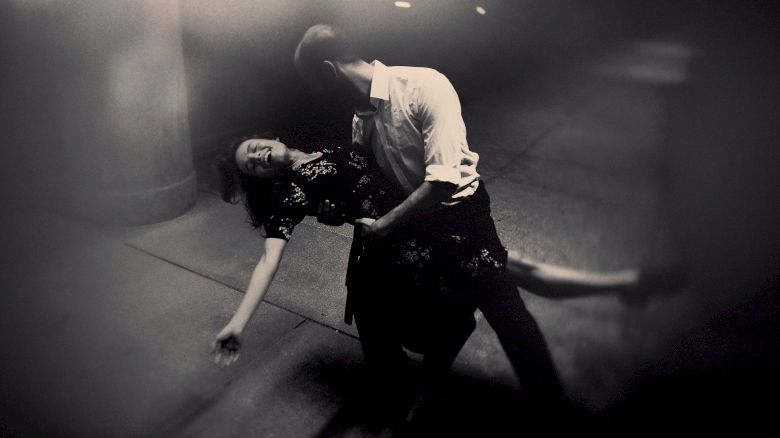 A man dips a woman in a dramatic dance pose on a dimly lit street.