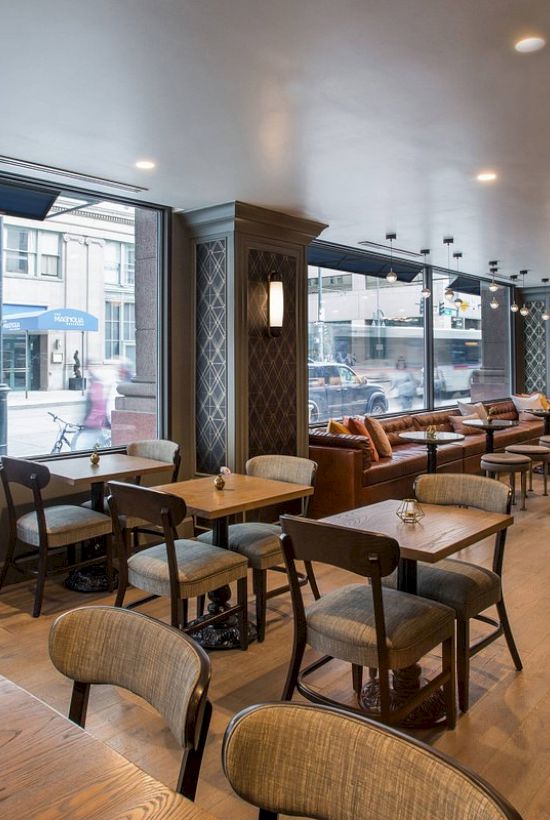 The image shows a modern, empty café with wooden tables and chairs, large windows, and street view.