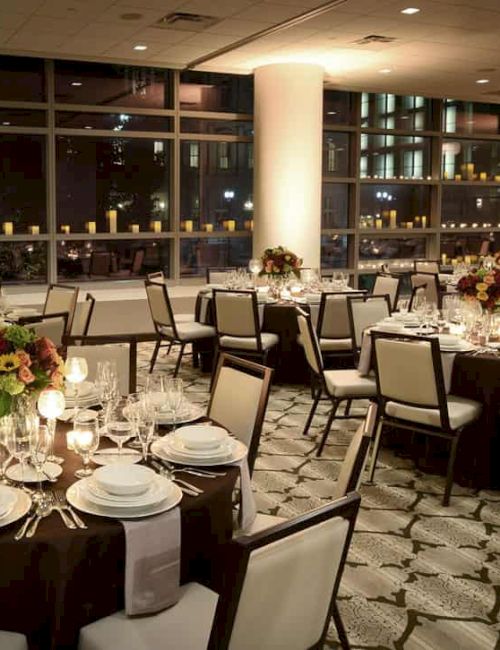 The image shows an elegant banquet hall with decorated tables, chairs, and soft lighting, set for a formal event or dinner.