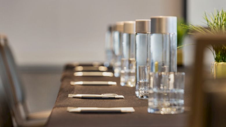 A conference table set with notebooks, pens, and water bottles, ready for a meeting.