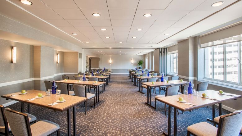 A modern conference room with multiple tables and chairs, neatly set with water bottles and notepads, ready for a meeting or event.