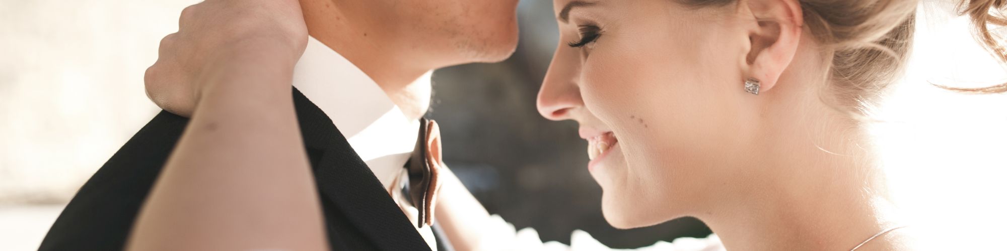 A couple dressed for a formal occasion shares an intimate moment, with the woman in a gown and the man in a suit.