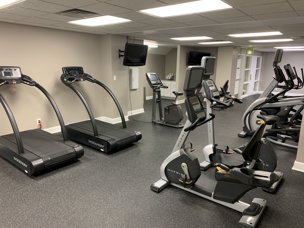 The image shows a gym with treadmills, exercise bikes, and other fitness equipment in a well-lit room.