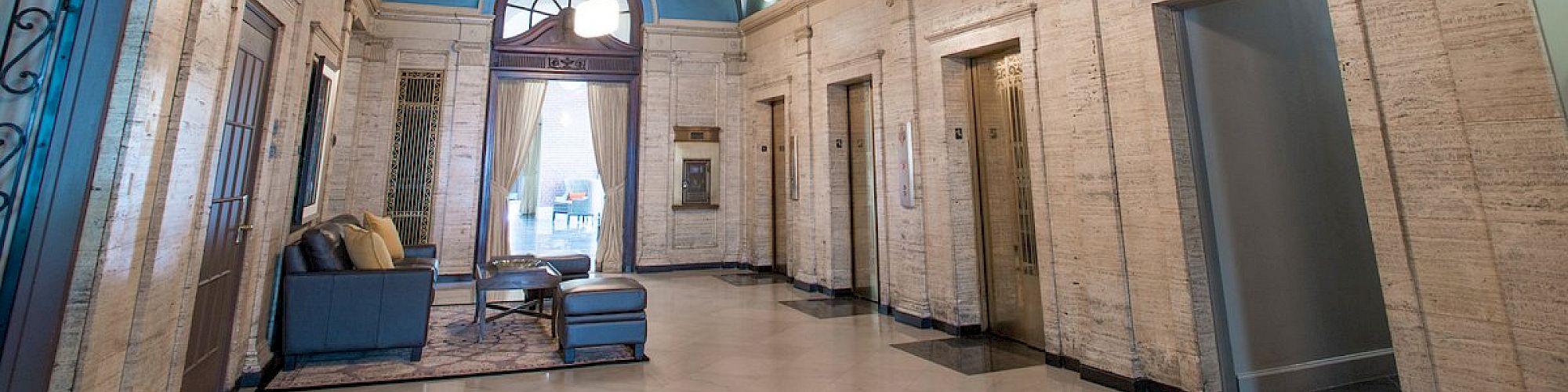 An elegant lobby with arched ceilings, elevators, a seating area, and decorative wall accents.