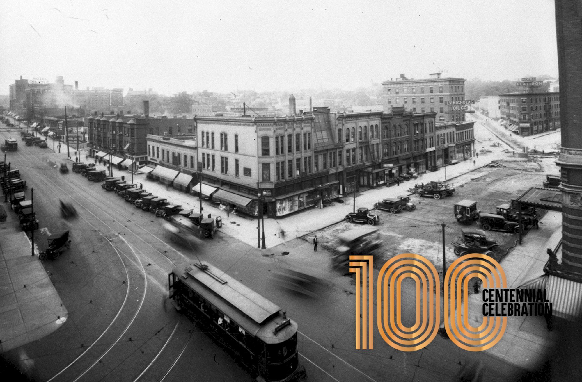 A vintage street scene with a streetcar, old buildings, and cars. 