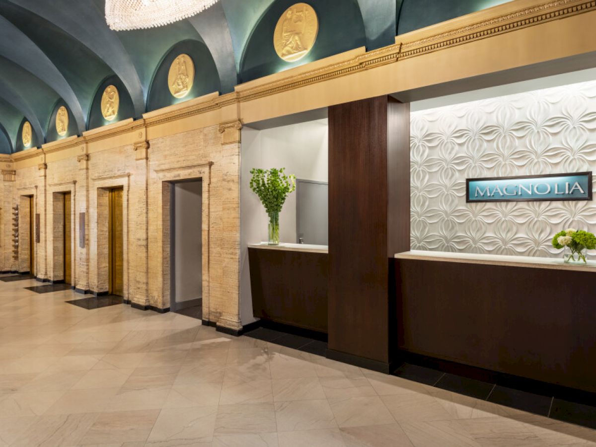 An elegant hotel lobby with decorative walls, elevators, and a reception desk labeled 