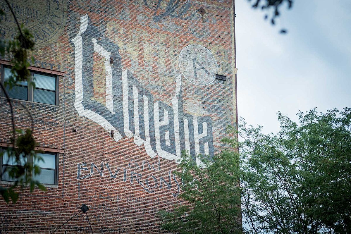 The image shows a building wall mural with the word