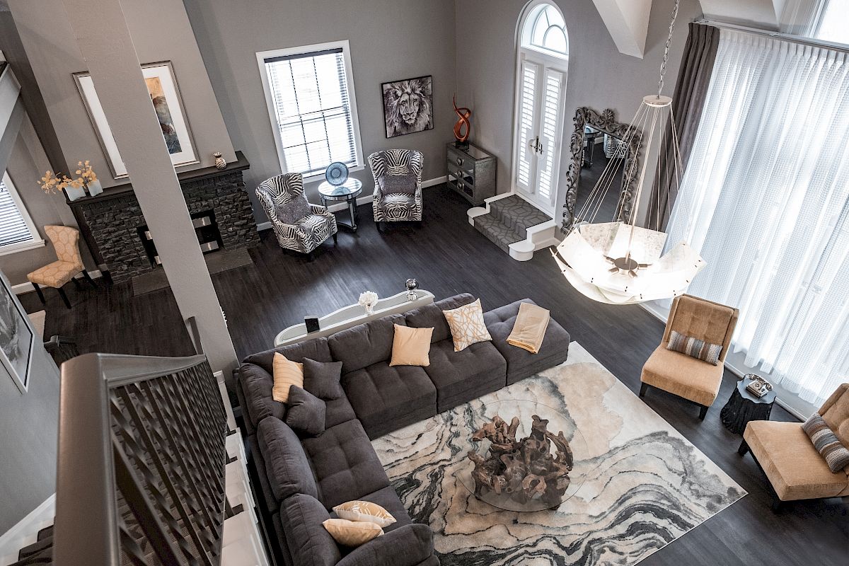 An elegant living room with a large sectional sofa, armchairs, chandelier, and marble-patterned rug.
